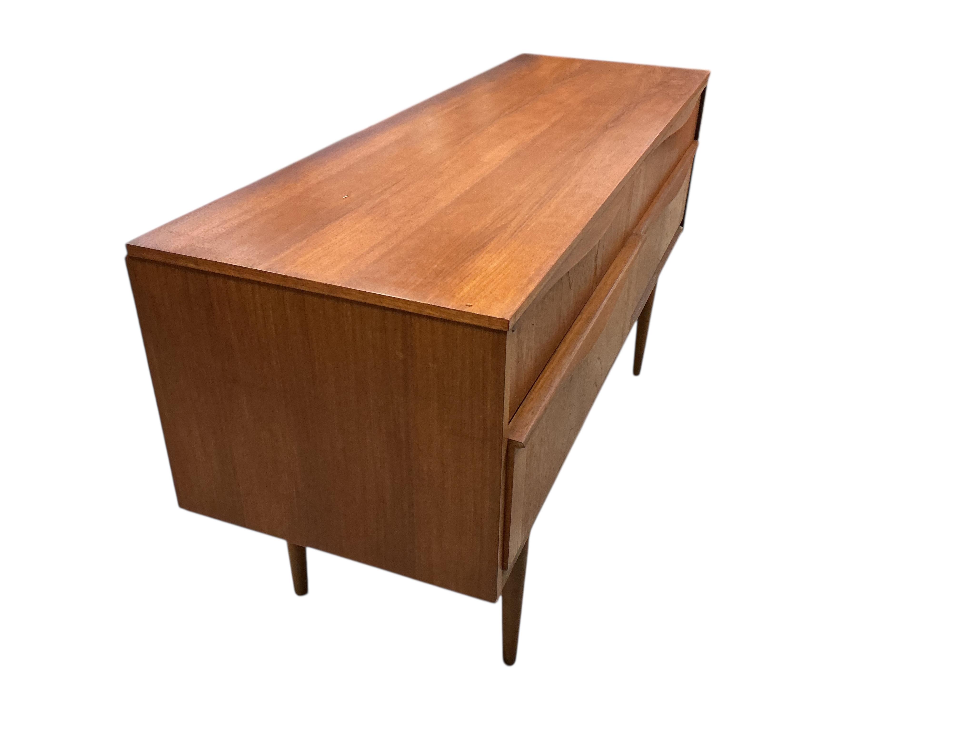 A mid century teak four drawer chest, width 124cm, depth 42cm, height 66cm